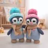 Crochet Penguin Duo with colorful pom-pom hats and scarves stand on floor. A cozy nursery background adds warmth and charm.