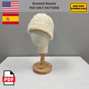 Cream-colored knitted beanie with a braided texture displayed on a beige mannequin head mounted on a wooden stand, set against a plain gray background. Text on the image reads ‘Braided Beanie PDF Knit Pattern,’ with U.S. and Spanish flags indicating language options, a yellow ‘Instant Download’ label, and a red PDF icon.