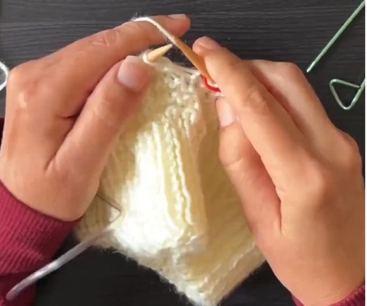 Ruth's hands knitting a cream-colored piece