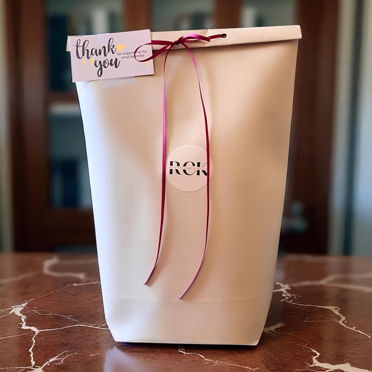 A wrapped RCK gift bag with a 'thank you' tag and ribbon