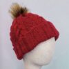 Handmade knit beanie in autumn red with a soft faux fur pom pom, cozy braided design, warm winter hat ideal as a unisex gift for him or her.